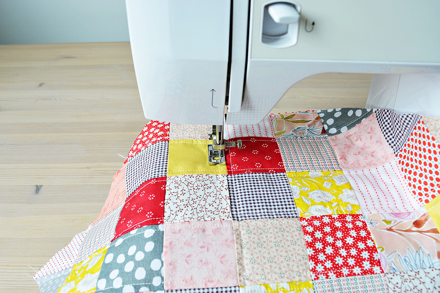 Quilting process: quilt and sewing machine on wooden desk